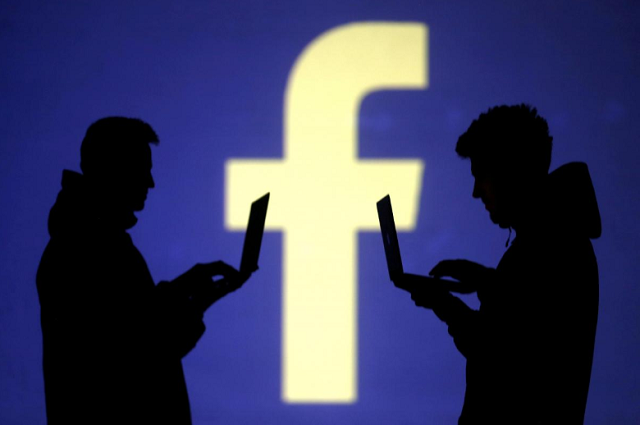 silhouettes of laptop users are seen next to a screen projection of facebook logo in this picture illustration taken march 28 2018 photo reuters