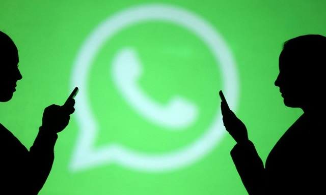 silhouettes of mobile users next to a screen projection of the whatsapp logo photo reuters