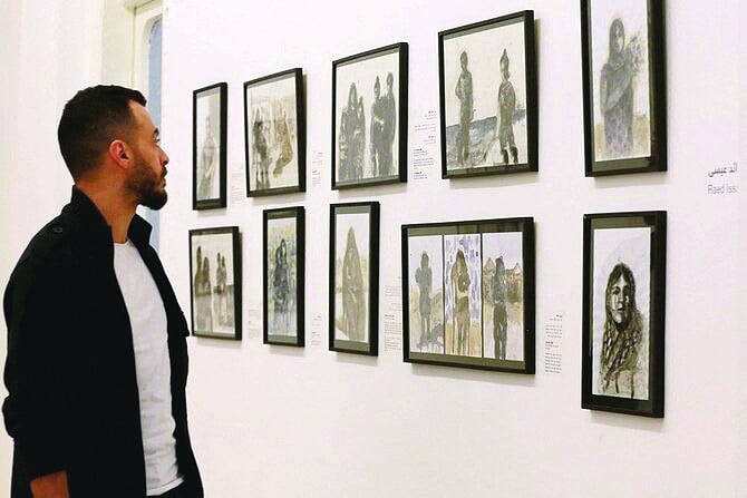 visitors observe art depicting gaza s harsh reality at daratal funun gallery photo afp