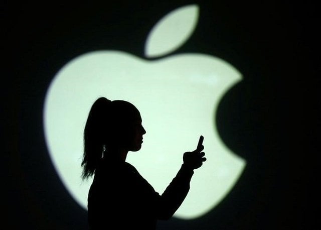 silhouette of mobile user is seen next to a screen projection of apple logo in this picture illustration taken march 28 2018 photo reuters