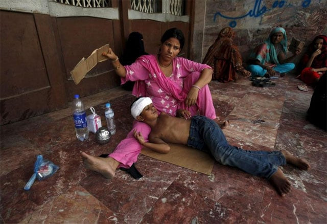 a woman uses a piece of cardboard to fan her son while waiting for their turn for a medical checkup outside jpmc during intense hot weather in karach june 23 2015 photo reuters a woman uses a piece of cardboard to fan her son while waiting for their turn for a medical checkup outside jpmc during intense hot weather in karach june 23 2015 photo reuters
