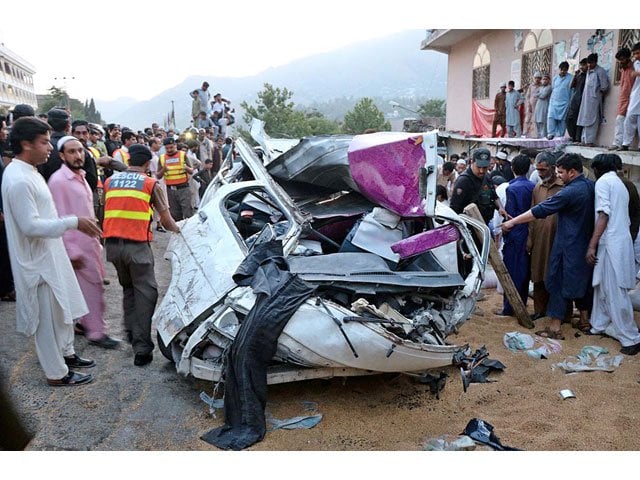 officials and locals gather around a car damaged after being hit by a goods truck in abbottabad on may 10 2018 photo app