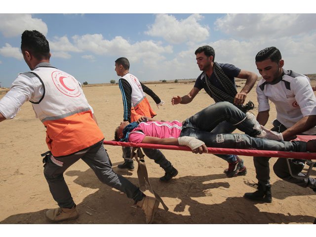 palestinians carry a protester injured during clashes with israeli forces along the border with the gaza strip east of khan yunis on may 14 2018 as palestinians protest over the inauguration of the us embassy following its controversial move to jerusalem photo afp