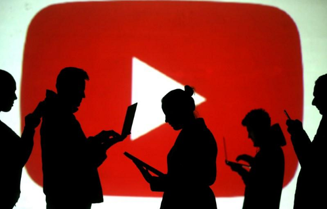 silhouettes of laptop and mobile device users are seen next to a screen projection of youtube logo in this picture illustration taken march 28 2018 photo reuters