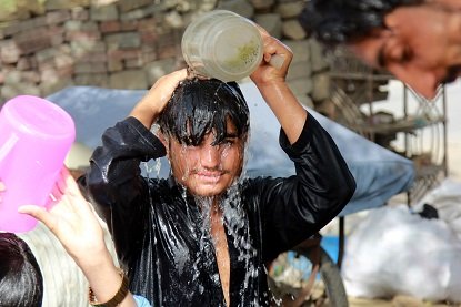 a young boy cools himself off with a bucket of water on a hot day in karachi photo athar khan express