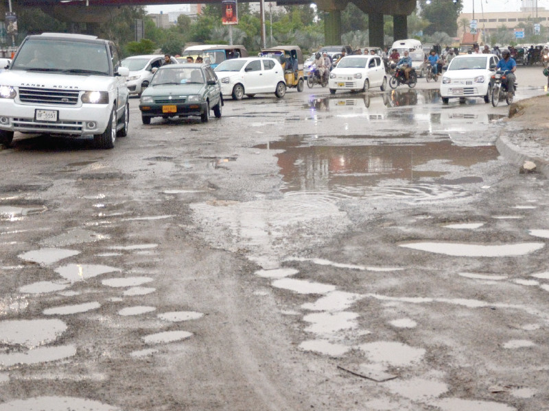 commuters try to avoid potholes on a road in the city the recent downpour has created craters on many roads exposing the quality of the work of the civic authorities photo express