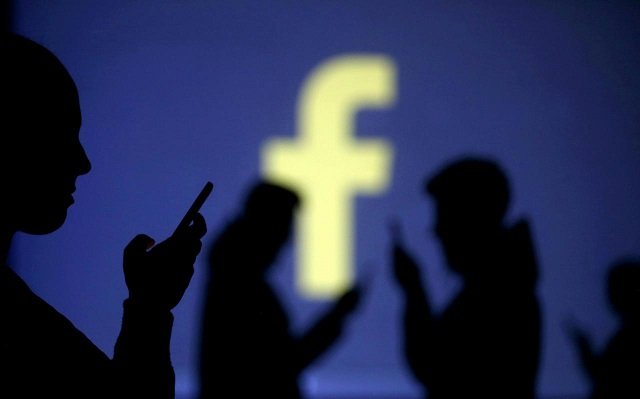 silhouettes of mobile users are seen next to a screen projection of facebook logo in this picture illustration taken march 28 2018 photo reuters