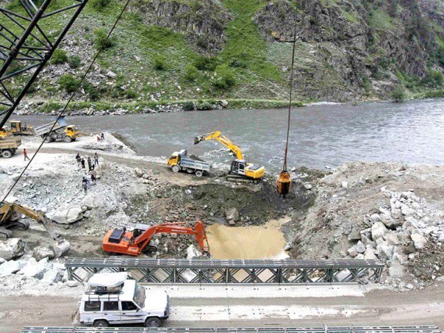 a private vehicle crosses a bridge as excavators are used at the dam site of kishanganga power project in gurez 160 km north of srinagar photo reuters