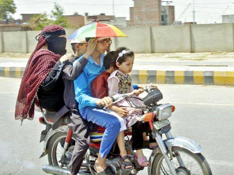 a boy dons an umbrella cap to ward off the harsh sun in lahore photo online