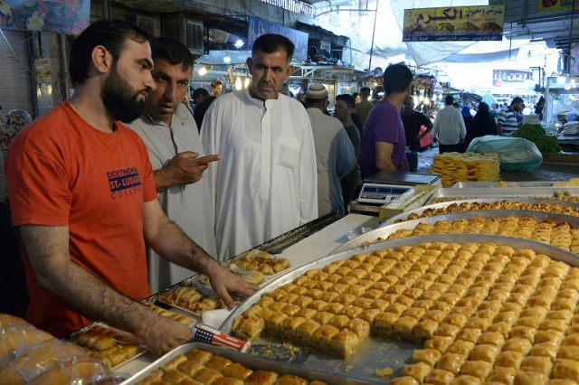 iraqi men buy food in an open air market after breaking the fast during the holy month of ramzan in the city of mosul photo afp