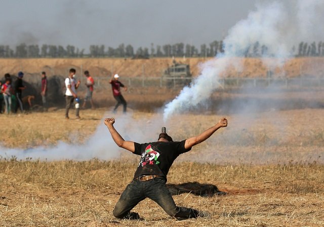 a palestinian protester holds a tear gas canister in his mouth during a demonstration along the border with israel east of khan yunis in the southern gaza strip on june 1 2018 photo afp