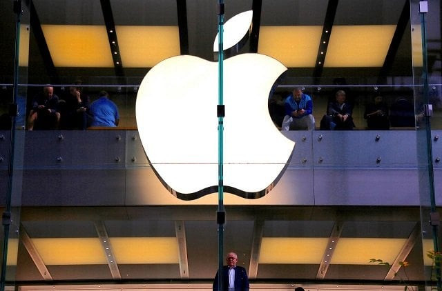a customer stands underneath an illuminated apple logo as he looks out the window of the apple store located in central sydney australia may 28 2018 photo reuters