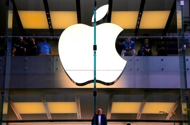a customer stands underneath an illuminated apple logo as he looks out the window of the apple store located in central sydney australia may 28 2018 photo reuters