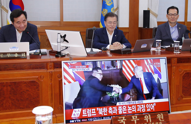 south korean president moon jae in c and prime minister lee nak yon l watch a television screen showing the summit between us president donald trump and north korean leader kim jong un during a cabinet meeting at the presidential blue house in seoul on june 12 2018 donald trump and kim jong un have become on june 12 the first sitting us and north korean leaders to meet shake hands and negotiate to end a decades old nuclear stand off photo afp