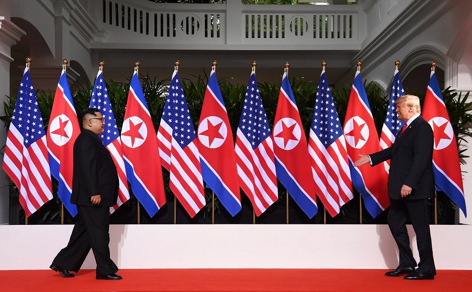 us president donald trump r and north korea s leader kim jong un l walk toward one another at the start of their historic us north korea summit photo afp