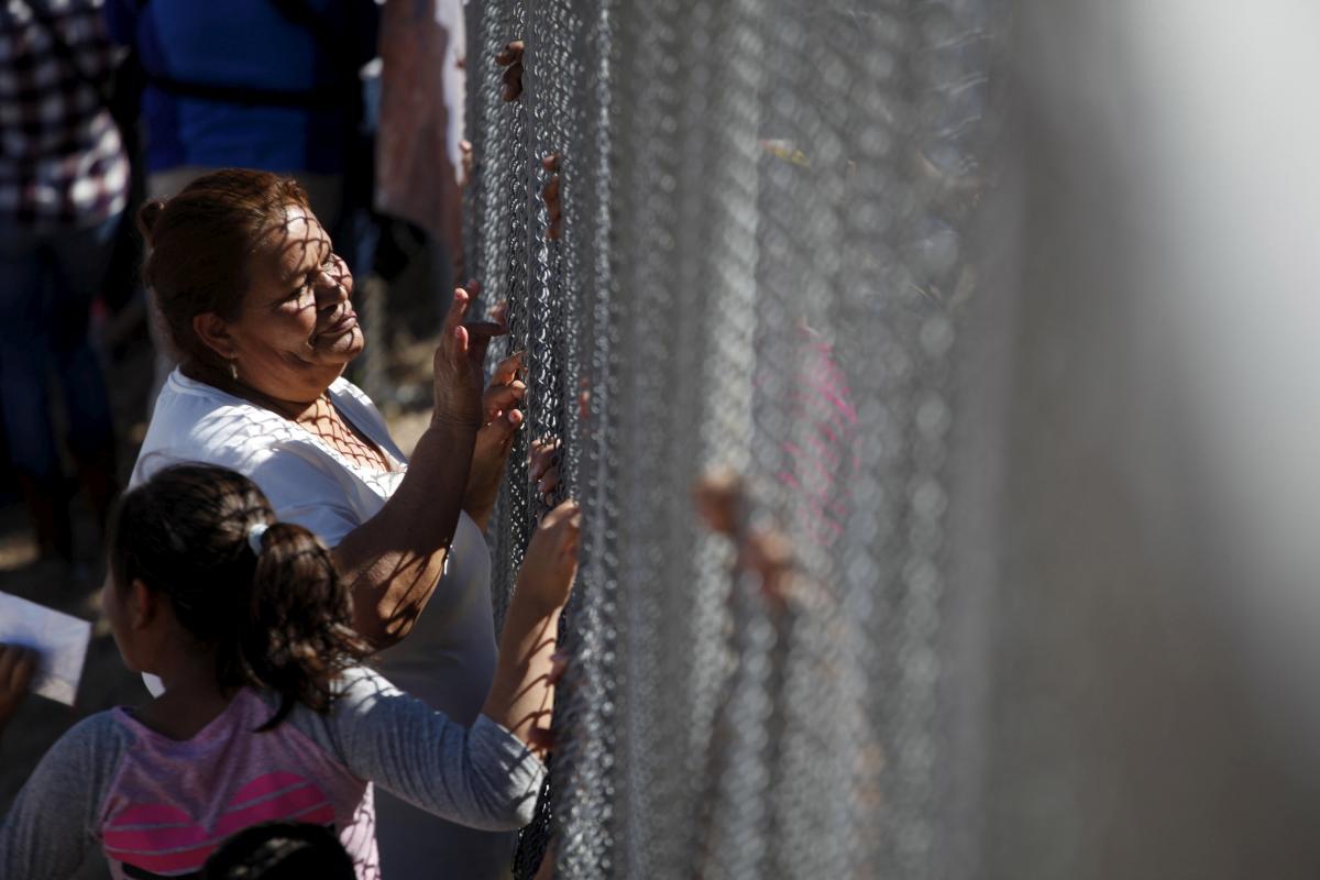 a woman touches a family member through the border fence between ciudad juarez and el paso united states after a bi national mass in support of migrants in ciudad juarez mexico photo reuters