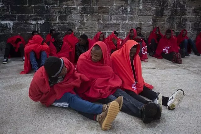 migrants keep warm in red cross blankets upon their arrival aboard a coast guard boat at tarifa 039 s harbour photo afp migrants keep warm in red cross blankets upon their arrival aboard a coast guard boat at tarifa 039 s harbour photo afp