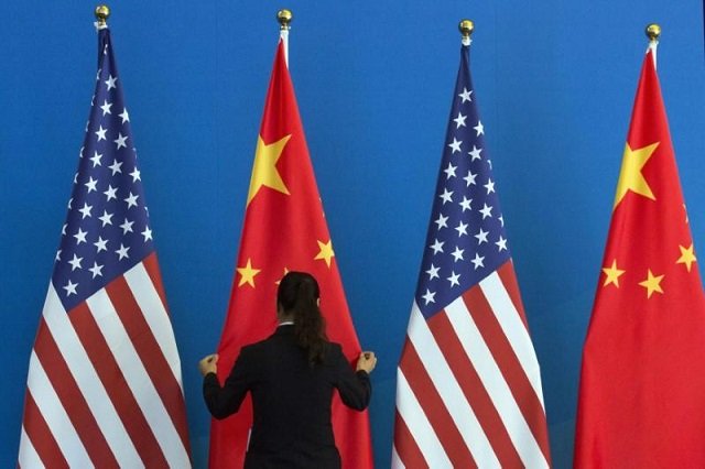 a chinese woman adjusts a chinese national flag next to u s national flags before a strategic dialogue expanded meeting part of the u s  china strategic and economic dialogue s amp ed held at the diaoyutai state guesthouse in beijing july 10 2014 photo reuters