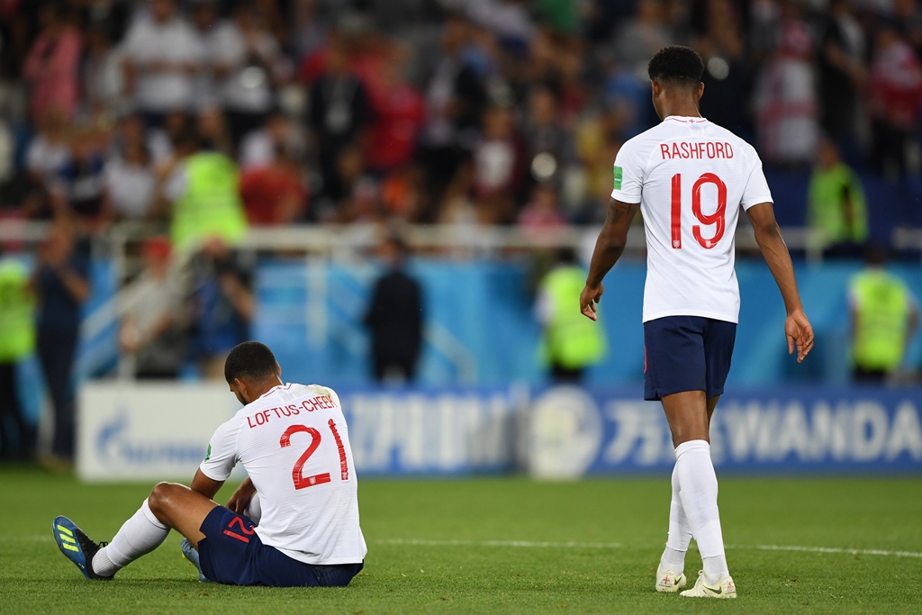 disappointed england midfielder ruben loftus cheek sits on the ground as forward marcus rashford walks past after their defeat to belgium photo afp
