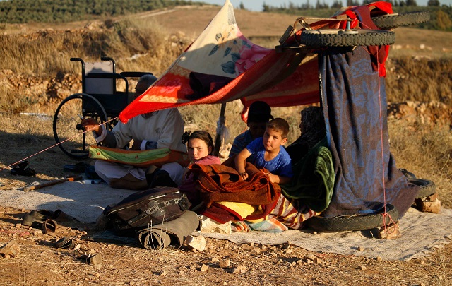 displaced syrians from the daraa province fleeing shelling by pro government forces wait in a makeshift camp to cross the jordanian border near the town of nasib southern syria on july 1 2018 photo afp