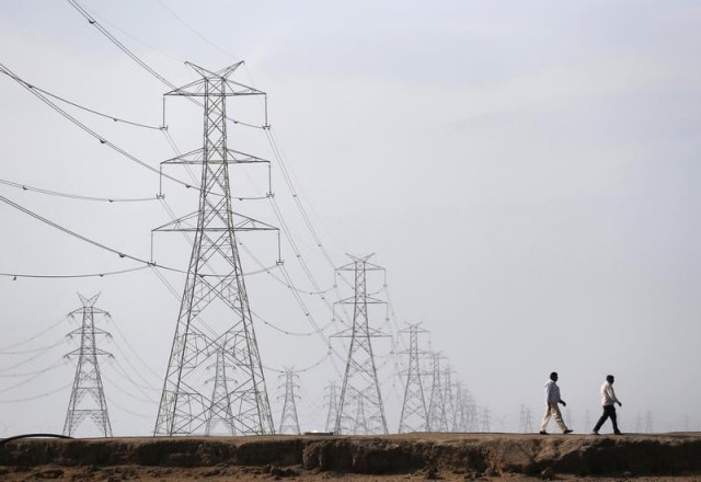 men walk past electric pylons photo reuters men walk past electric pylons photo reuters