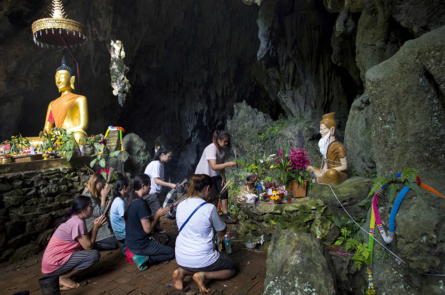 family members pray before a shrine in tham luang cave area as operations continue for the 12 boys and their coach trapped at the cave at khun nam nang non forest park in the mae sai district photo afp