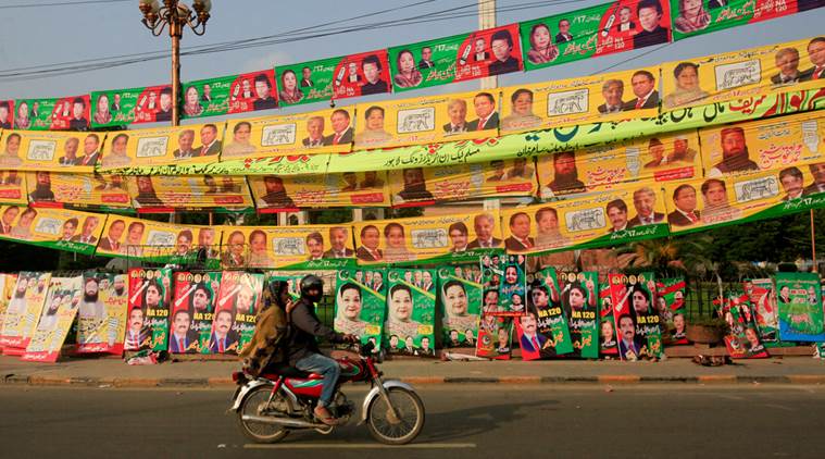 residents ride on bike past election campaign signs along a road in lahore pakistan photo reuters