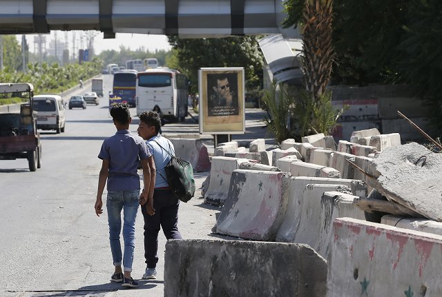 syrians walk past cement blocks on the side of the road after a security barrier was removed from the area in damascus photo afp syrians walk past cement blocks on the side of the road after a security barrier was removed from the area in damascus photo afp