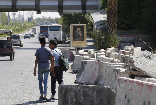 syrians walk past cement blocks on the side of the road after a security barrier was removed from the area in damascus photo afp