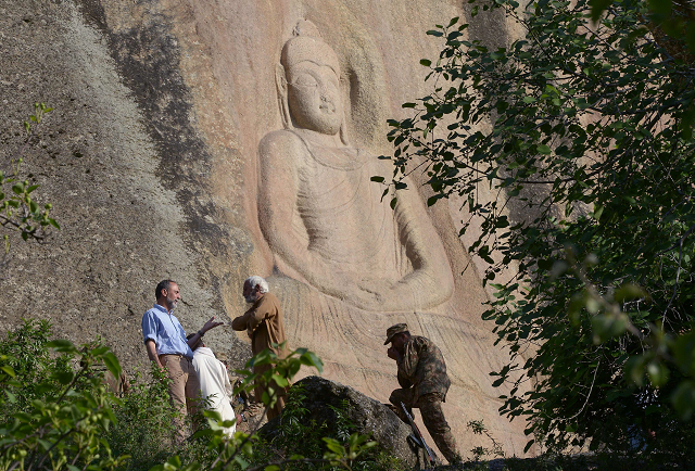 experts speak next to the seventh century rock sculpture of a seated buddha carved into mountain in jahanabad town in swat photo afp