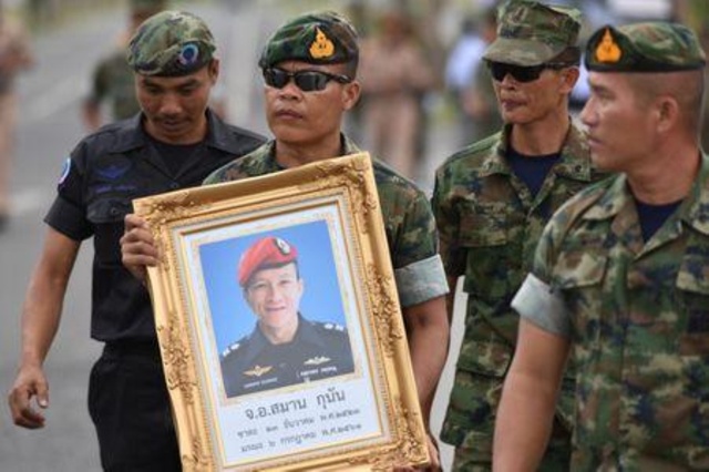 an honour guard hold up a picture of samarn kunan 38 a former member of thailand 039 s elite navy seal unit who died working to save 12 boys and their soccer coach trapped inside a flooded cave at an airport in rayong province thailand july 6 2018 photo reuters