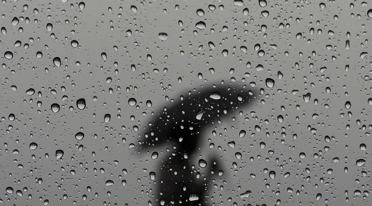 a woman carrying an umbrella is silhouetted from behind a window covered with rain drops photo reuters