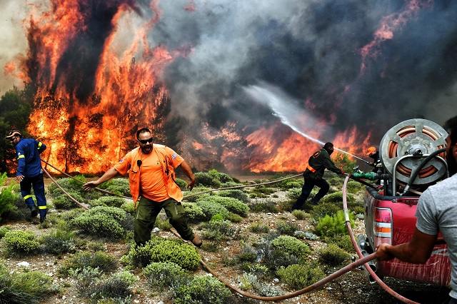 firefighters and volunteers try to extinguish flames during a wildfire at the village of kineta near athens on july 24 2018 raging wildfires killed 74 people including small children in greece photo afp