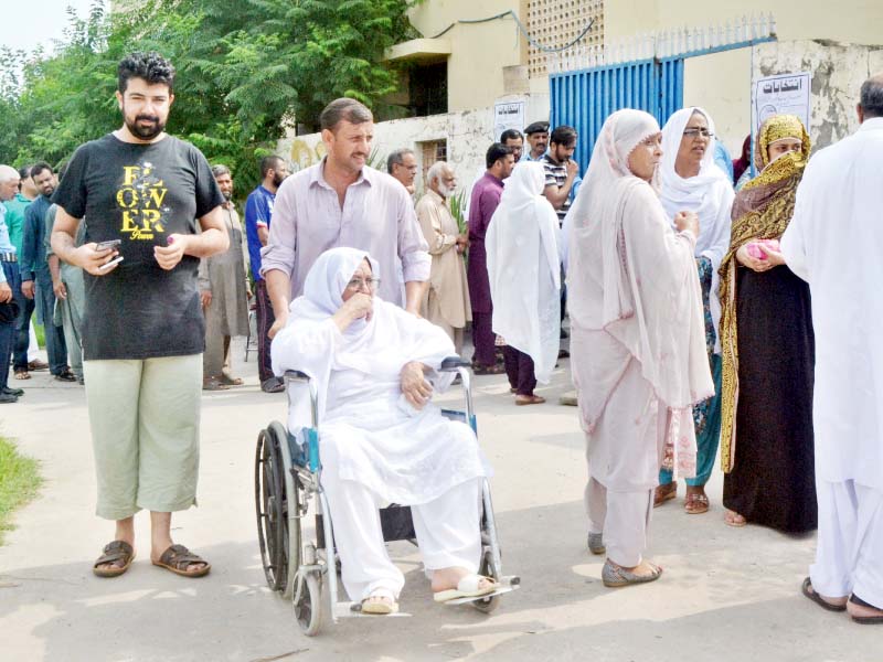 a man wheels his elderly mother out of a polling station in islamabad photo waseem nazir express