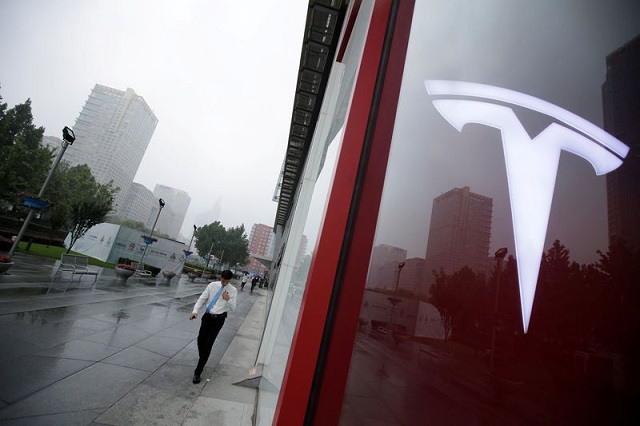 a man walks near a logo of tesla outside its china headquarters at china central mall in beijing china july 11 2018 photo reuters