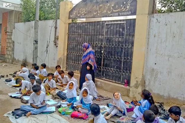 students of ali muhammad iqbal government school in gulshan e iqbal had to take classes on the road outside the school after it was found locked in the morning photo inp