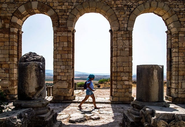 in this file photo taken on july 25 2018 a tourist walks through the ruins of the ancient roman site of volubilis near the town of moulay idriss zerhounon in morocco 039 s north central meknes region situated in the centre of a fertile plain at the foot of mount zerhoun the towering remains of morocco 039 s oldest roman site volubilis were long neglected but after decades of looting and decay custodians of the now closely guarded ancient city are turning the page and attracting back tourists photo afp
