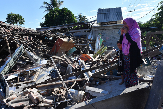 a woman and boy watch as men clear the wreckage of houses damaged by an earthquake in menggala photo afp a woman and boy watch as men clear the wreckage of houses damaged by an earthquake in menggala photo afp