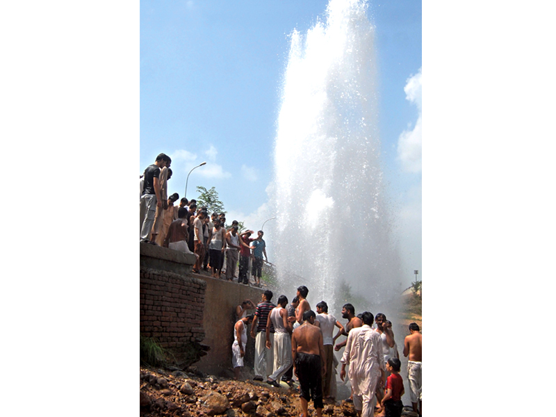 water gushes from a damaged water line as a crowd gathers photo express file