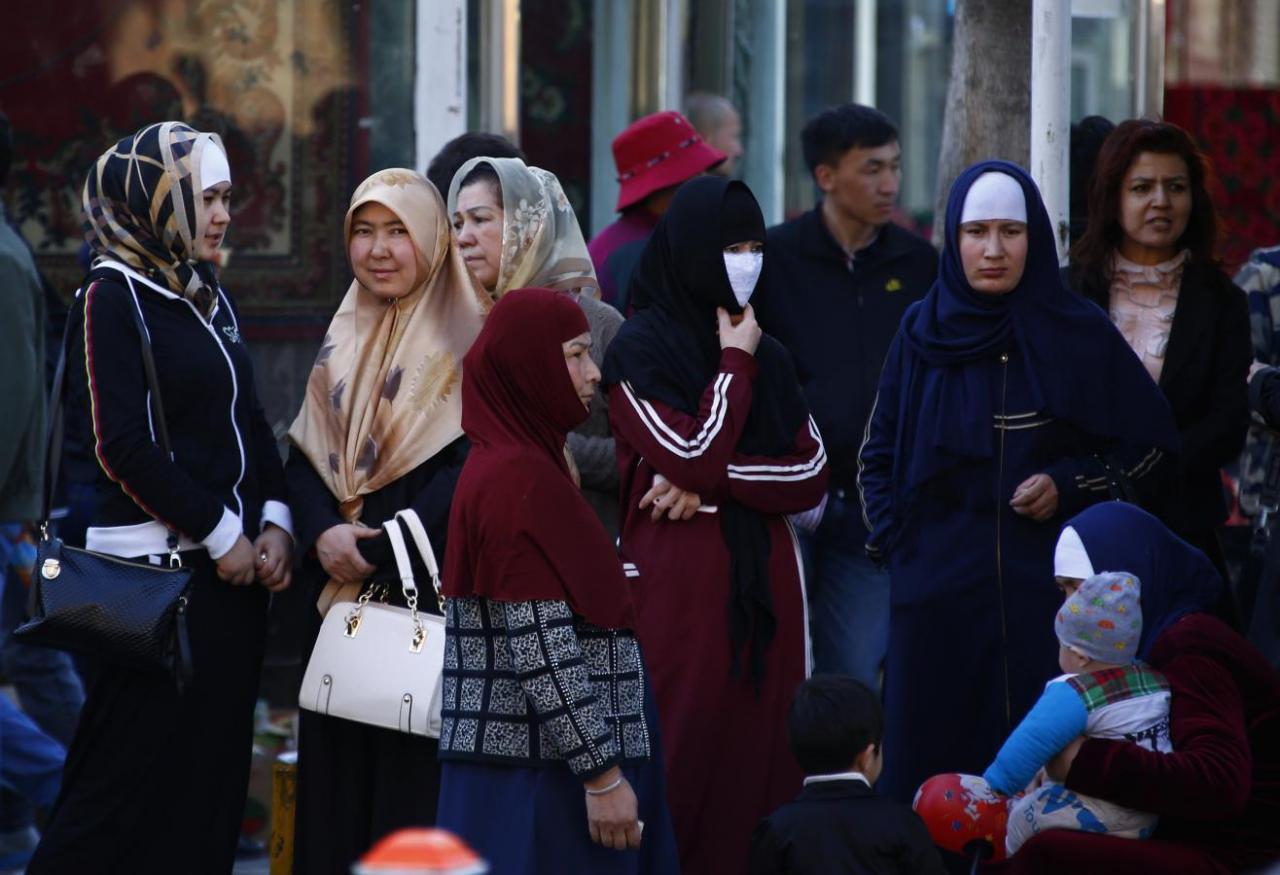 uighur women stand next to a street to wait for a bus in downtown urumqi xinjiang uighur autonomous region photo reuters