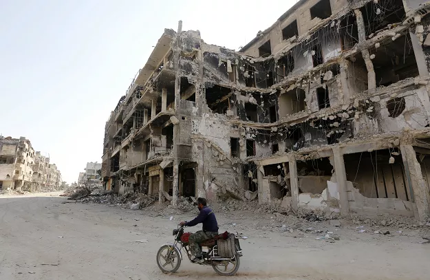 a man rides a motorbike by destroyed buildings in harasta on the outskirt of the syrian capital damascus photo afp a man rides a motorbike by destroyed buildings in harasta on the outskirt of the syrian capital damascus photo afp