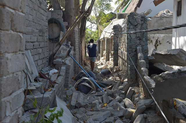 a man walks through rubble of buildings on gili air island west nusa tenggara photo afp