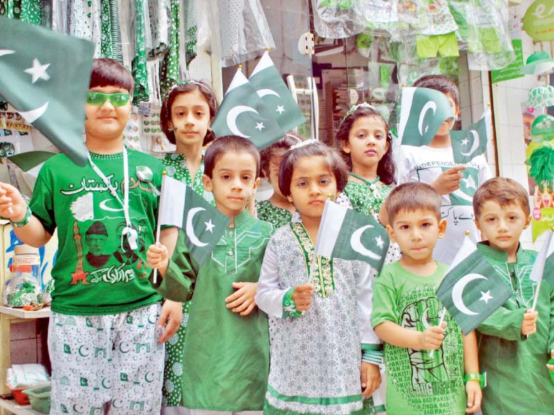 children dressed in flag themed clothes while a man gets his car decorated in green and white photo express agencies