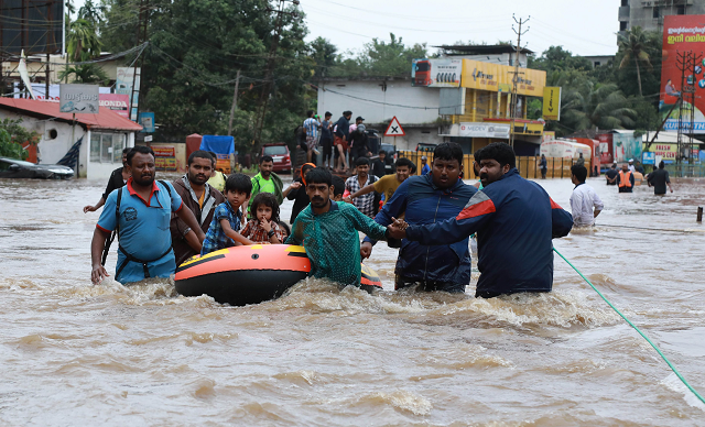 indian volunteers and rescue personal evacuate local residents in a boat in a residential area at aluva in ernakulam district in the indian state of kerala photo afp