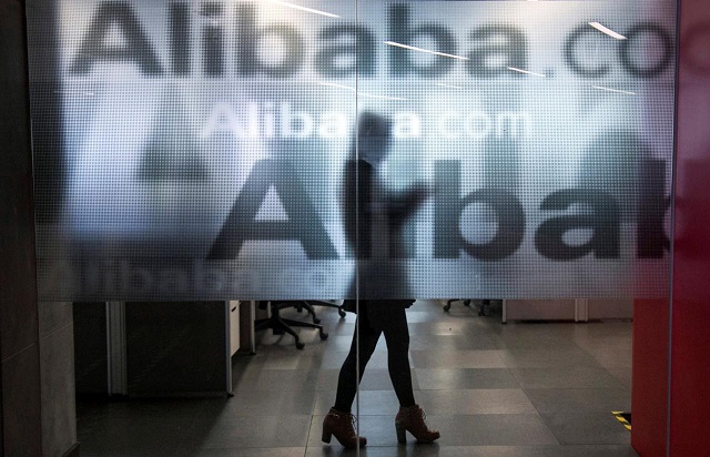 an employee is seen behind a glass wall with the logo of alibaba at the company 039 s headquarters on the outskirts of hangzhou zhejiang province april 23 2014 photo reuters
