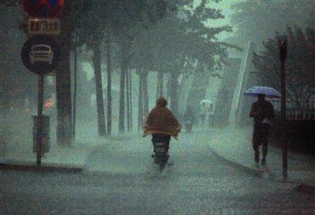 a man rides an electric bike as a pedestrian carries an umbrella during a heavy rain storm in beijing photo reuters