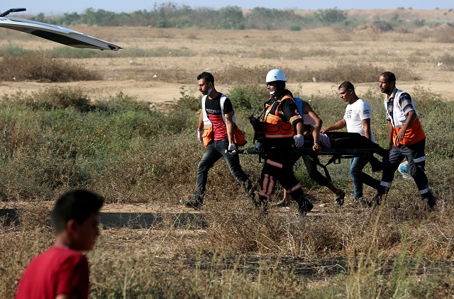 palestinian paramedics carry an injured protester during demonstrations at the israel gaza border east of khan yunis in the southern gaza strip on august 17 2018 photo afp