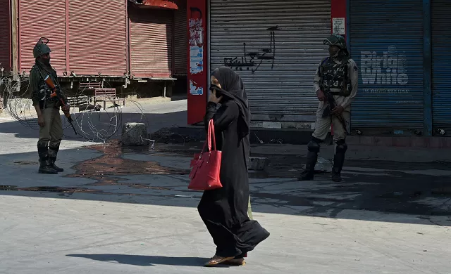indian paramilitary troopers stand guard as a kashmiri woman walks past during the first day of a strike photo afp indian paramilitary troopers stand guard as a kashmiri woman walks past during the first day of a strike photo afp