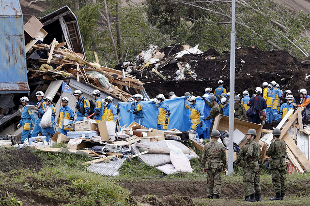 police officers and members of the japan self defense forces jsdf carry a missing person found from an area damaged by a landslide caused by an earthquake photo reuters