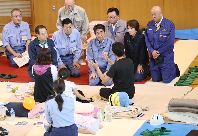 japanese prime minister shinzo abe talks to survivors in a shelter of the devastated city of atsuma photo afp